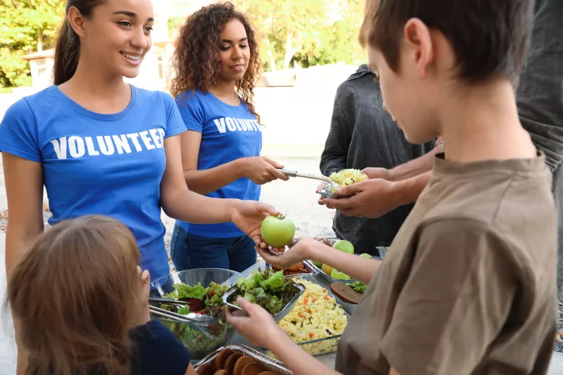 Volunteers serving food to people outdoors
